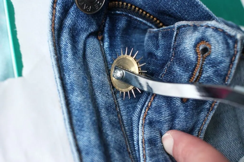 Tracing wheel being applied to the waistband seam on a pair of blue denim Fat Face jeans