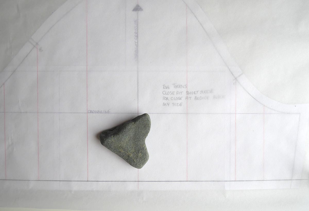 Basic sleeve block on table, with pattern making paper on top and a heart shaped stone weighing it down.