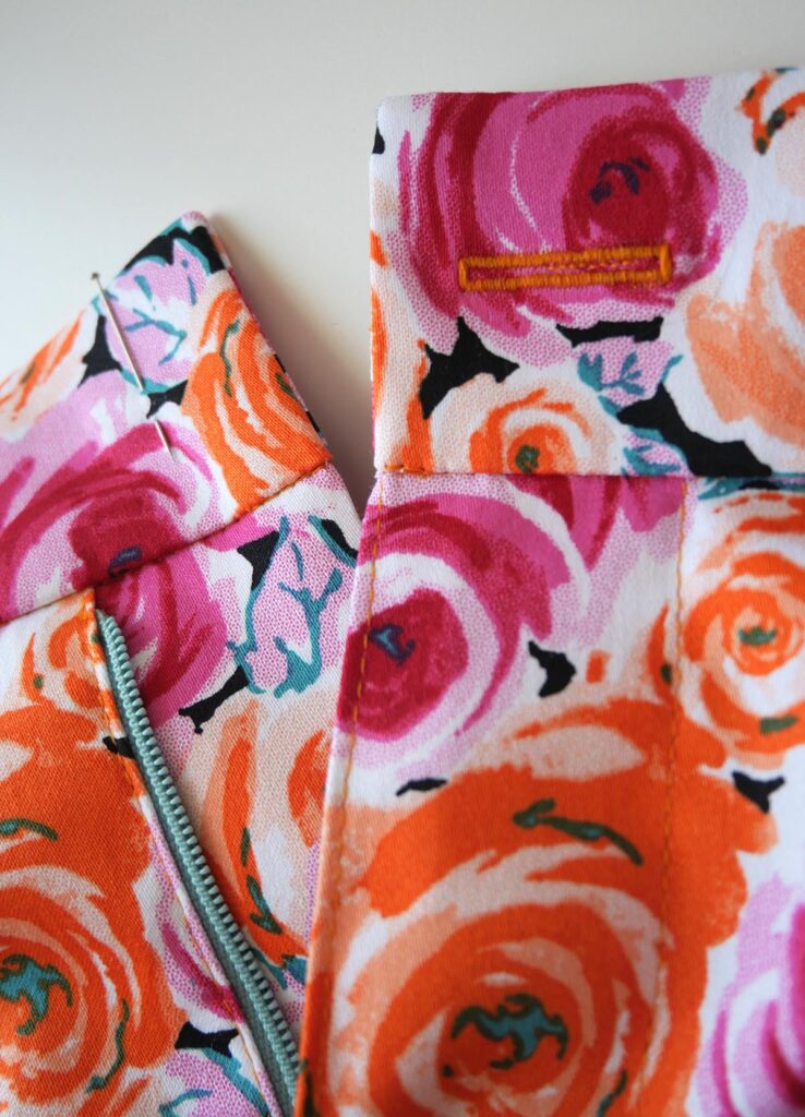 Machine buttonhole on bright pink and orange floral trousers