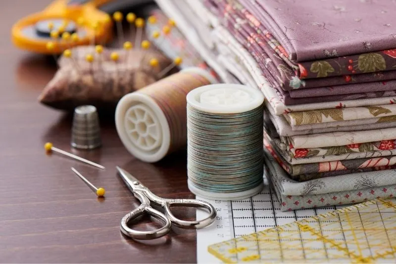 Folded fat quarter fabric pieces with two thread reels an d small thread scissors.