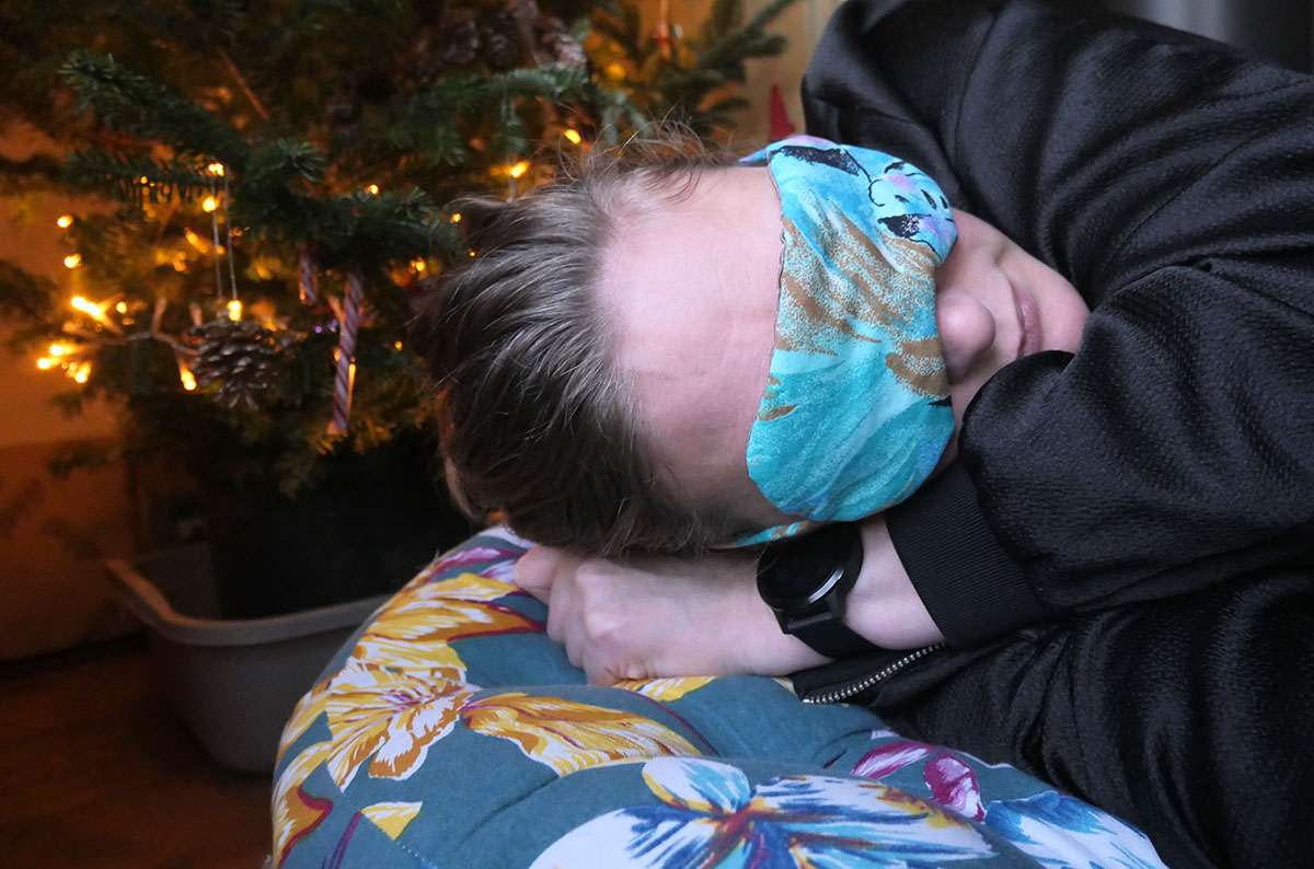 Eve Tokens sleeping in front of a Christmas tree with a DIY sleeping mask covering her eyes