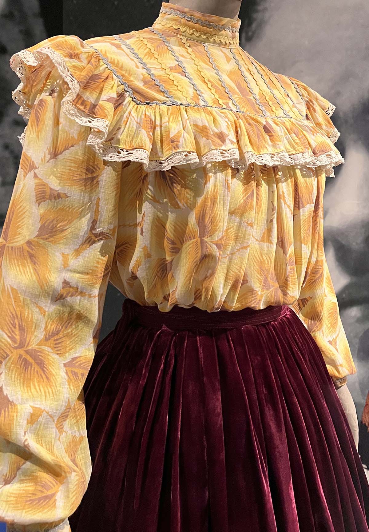 The vibrant yellow ruffled blouse paired with a deep burgundy velvet skirt
