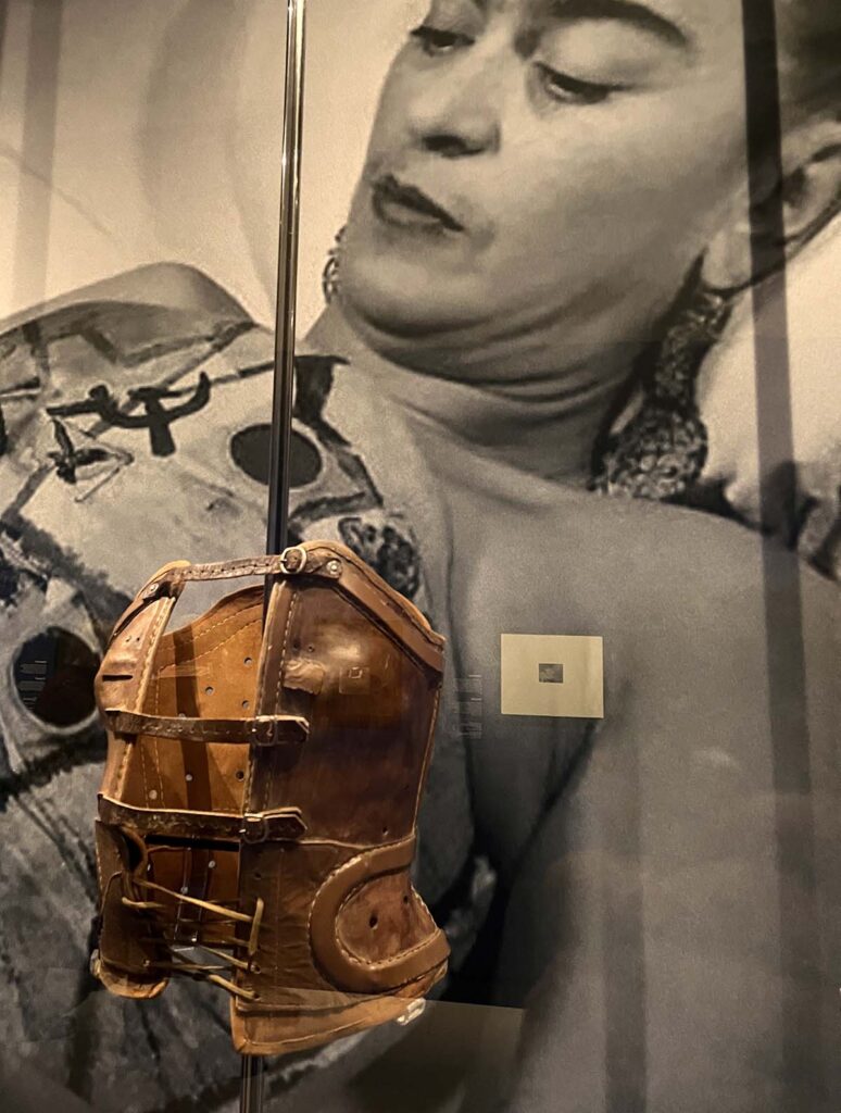 Frida Kahlo pictured on the wall behind a leather support corset