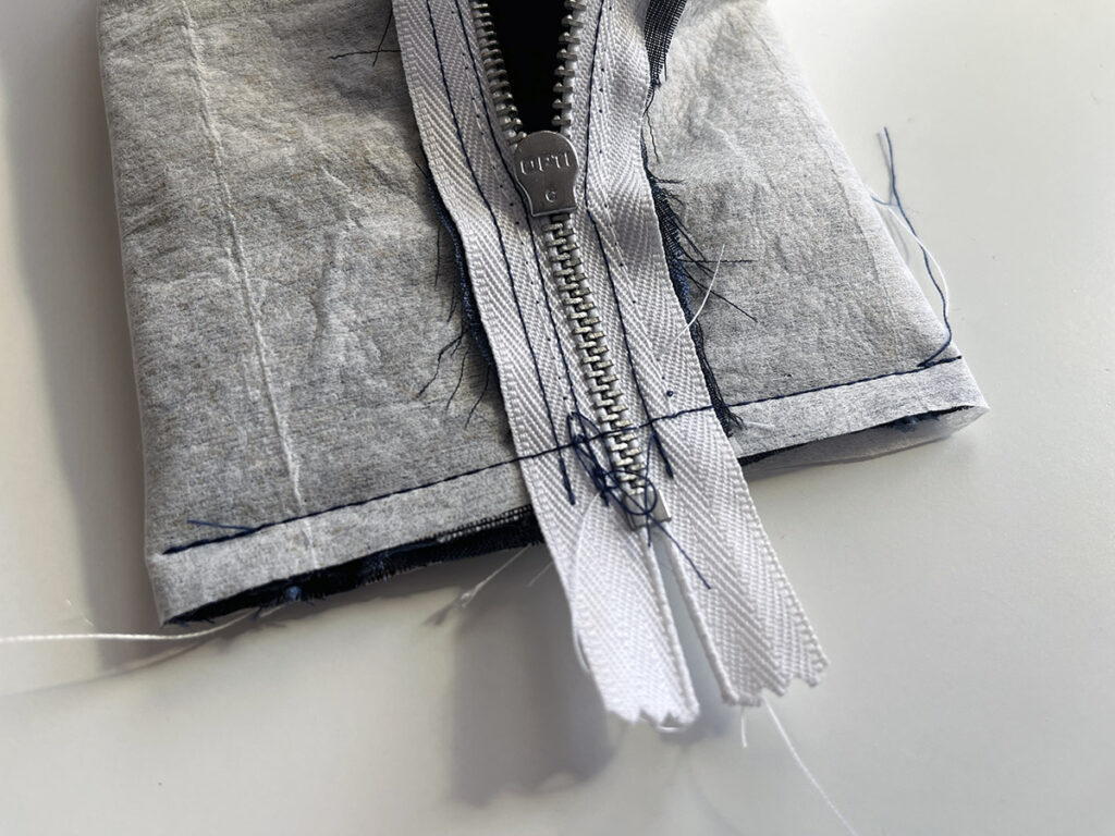 Sew one short edge, sewing carefully over the zipper, avoiding direct contact between the sewing needle and the zipper teeth!