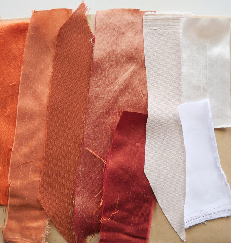 Selection of orange and cream fabrics laid on a brown envelope