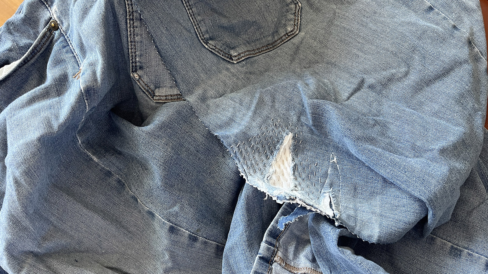 An old pair of stretch denim jeans with visible mending