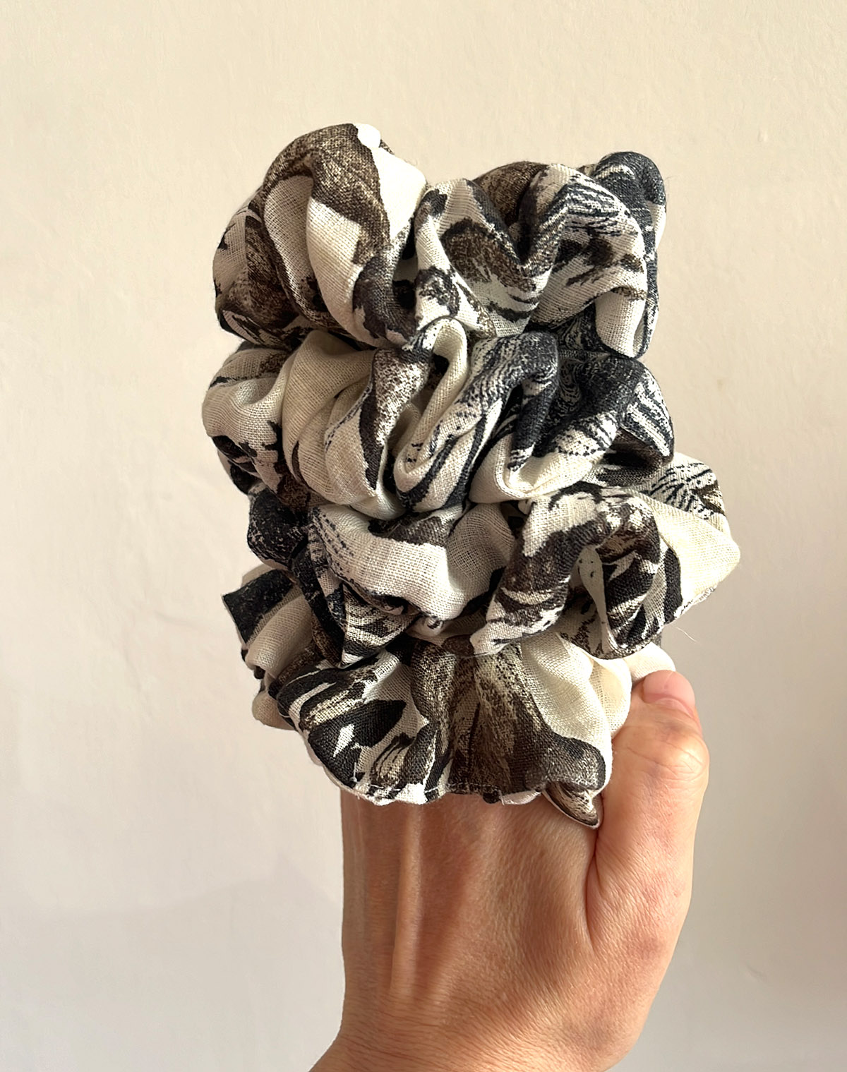 My gorgeous abstract linen chunky scrunchies held in my hand with a white background