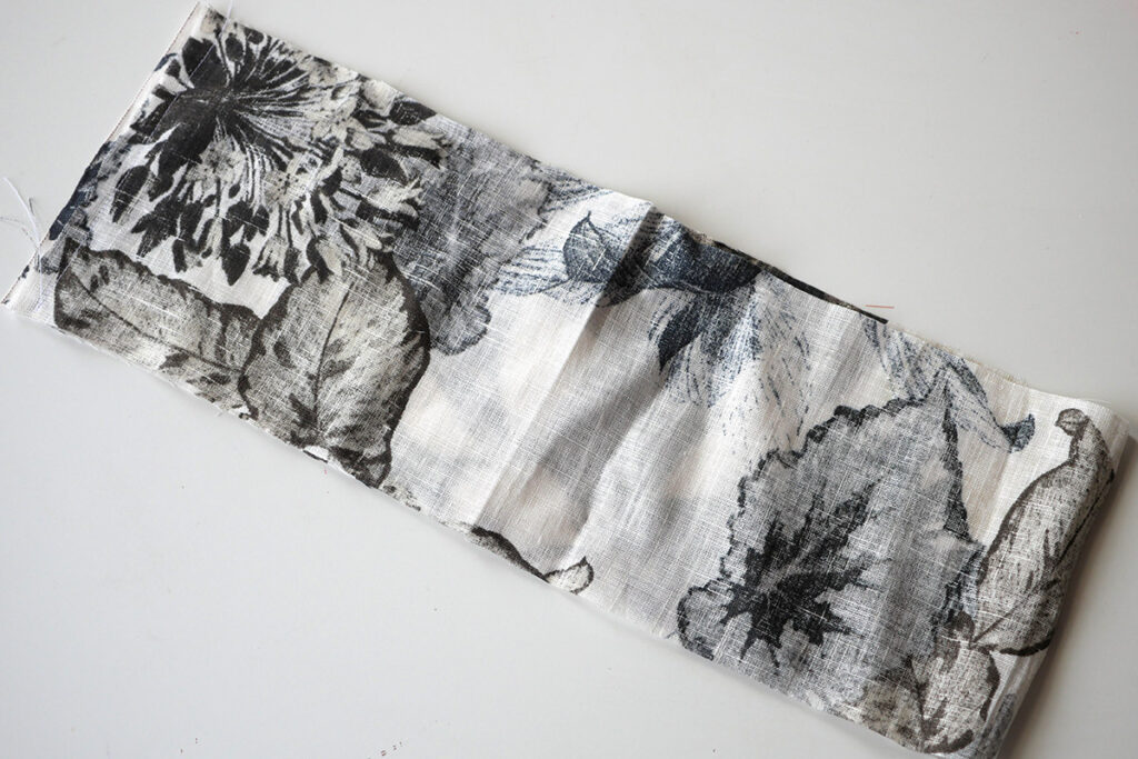 A piece of abstract floral linen in charcoal grey and blue on a white background