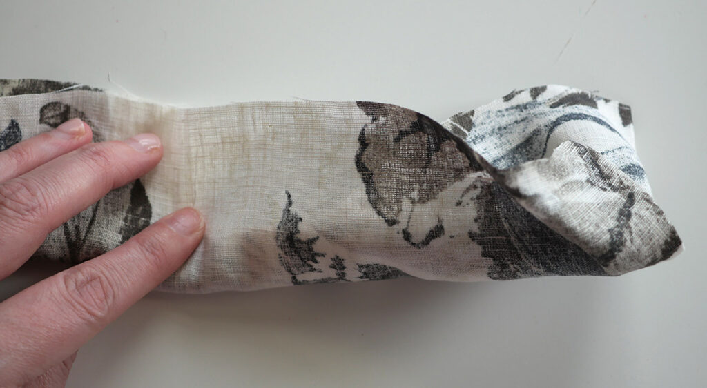 When sewing a scrunchie using the burrito method, the lower piece wraps over the folded piece